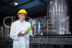 Factory worker examining a bottle in factory