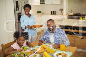 Portrait of happy woman serving food to the family