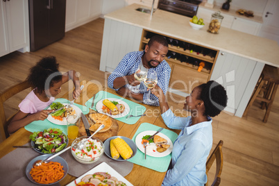 Family toasting glasses of wine while having meal on dining table