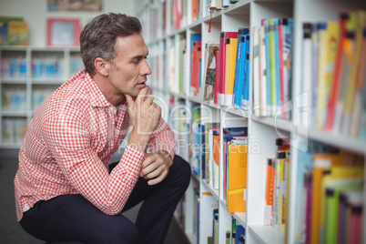 Thoughtful school teacher selecting book in library