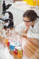 Thoughtful schoolgirl leaning on table in laboratory