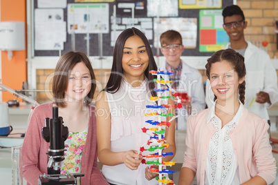 Portrait of happy students experimenting molecule model in laboratory