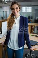 Smiling female executive standing in creative office