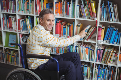 Portrait of disabled school teacher selecting book in library