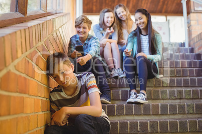 School friends bullying a sad boy in school corridor