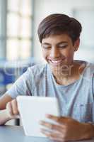 Happy schoolboy using digital tablet in classroom