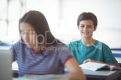 Portrait of happy schoolboy studying in classroom