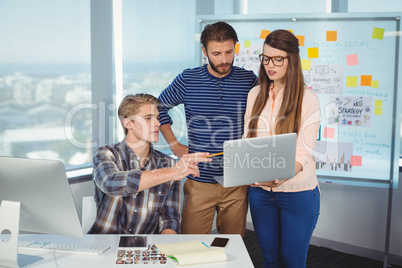 Graphic designers discussing over laptop