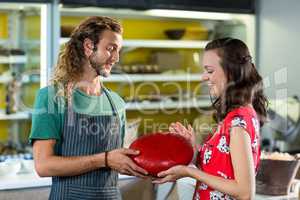 Salesman assisting costumer in buying gouda cheese at counter