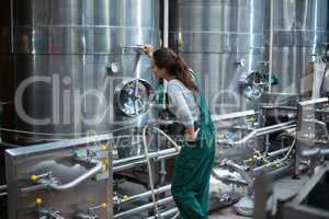 Female factory worker looking at control wheel of storage tank