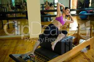 Determined woman practicing stretching exercise on reformer