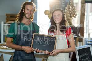 shop assistants holding open sign board