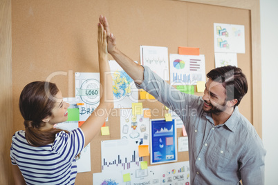 Male and female executives giving high five to each other
