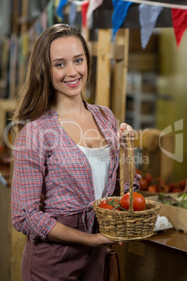 Smiling woman holding a basket of tomatoes in the grocery store