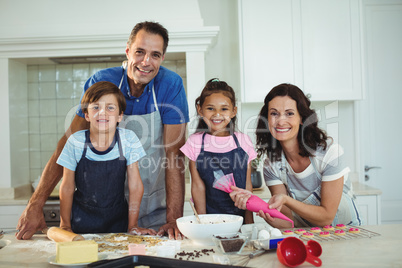 Portrait of happy family preparing cookies in kitchen