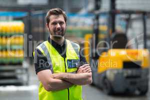 Factory worker standing with arms crossed in factory