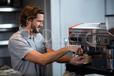 Male staff making cup of coffee at counter