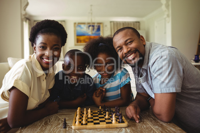 Portrait of family playing chess together at home in the living room