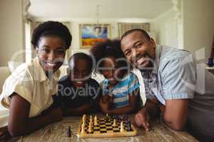 Portrait of family playing chess together at home in the living room