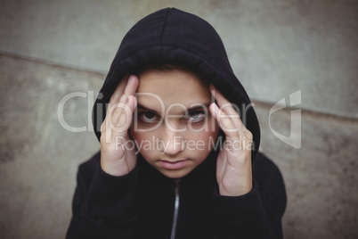 Anxious teenage girl in black hooded jacket looking at camera