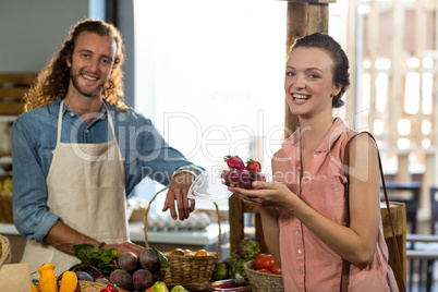 Woman holding a box of strawberries at the counter