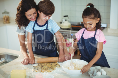 Mother and kids preparing cookies in kitchen