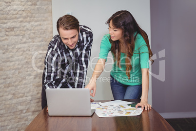 Male and graphic designers discussing over laptop