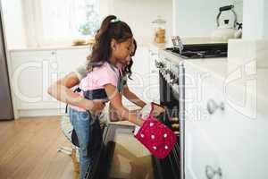 Mother and daughter placing tray of cookies in oven