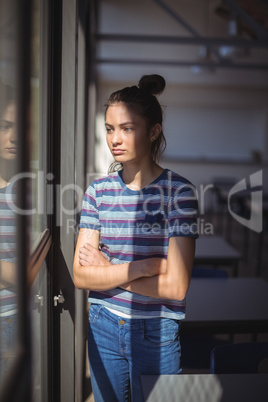 Schoolgirl standing with arms crossed in classroom