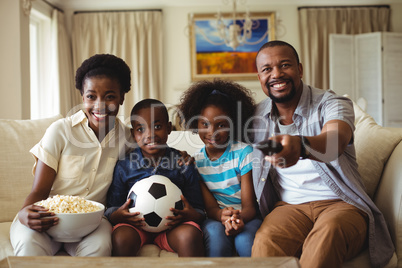 Parents and kids watching television in living room