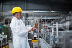 Factory worker examining a bottle in factory