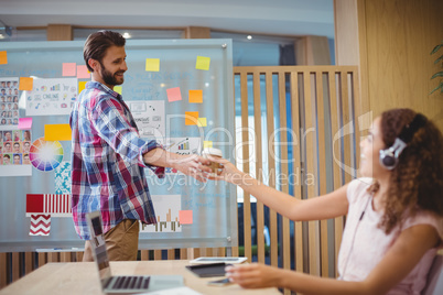 Graphic designer offering coffee to his colleague