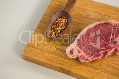 Sirloin chop and spices in wooden spoon on wooden board