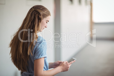 Schoolgirl using mobile phone in corridor