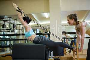 Female trainer assisting woman with stretching exercise