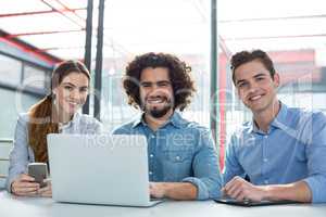 Portrait of smiling business executive discussing over laptop in meeting