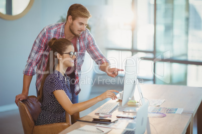 Graphic designers discussing over personal computer