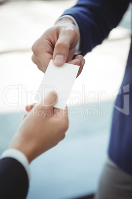 Businesswoman giving visiting card to businessman on platform