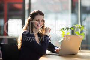 Portrait of female business executive sitting in office with laptop on table