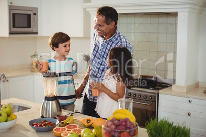 Father and kids holding glass of smoothie