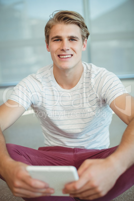 Portrait of male business executives sitting on floor and digital tablet