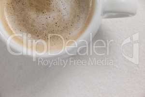 Close-up of white coffee cup with creamy froth