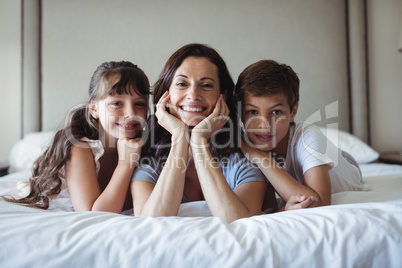 Mother and kids lying on bed in bedroom