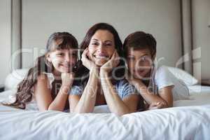 Mother and kids lying on bed in bedroom