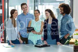 Smiling business team discussing over digital tablet in meeting