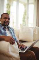 Man sitting on sofa and using laptop in living room