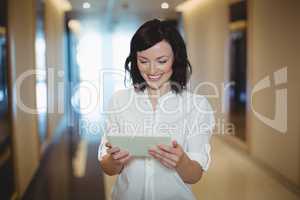 Female executive using digital tablet in corridor