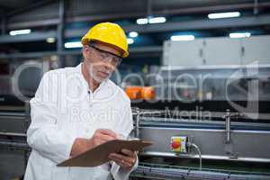 Factory engineer maintaining record on clipboard