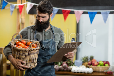 Vendor holding a clipboard and a basket of tomatoes