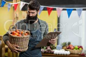 Vendor holding a clipboard and a basket of tomatoes
